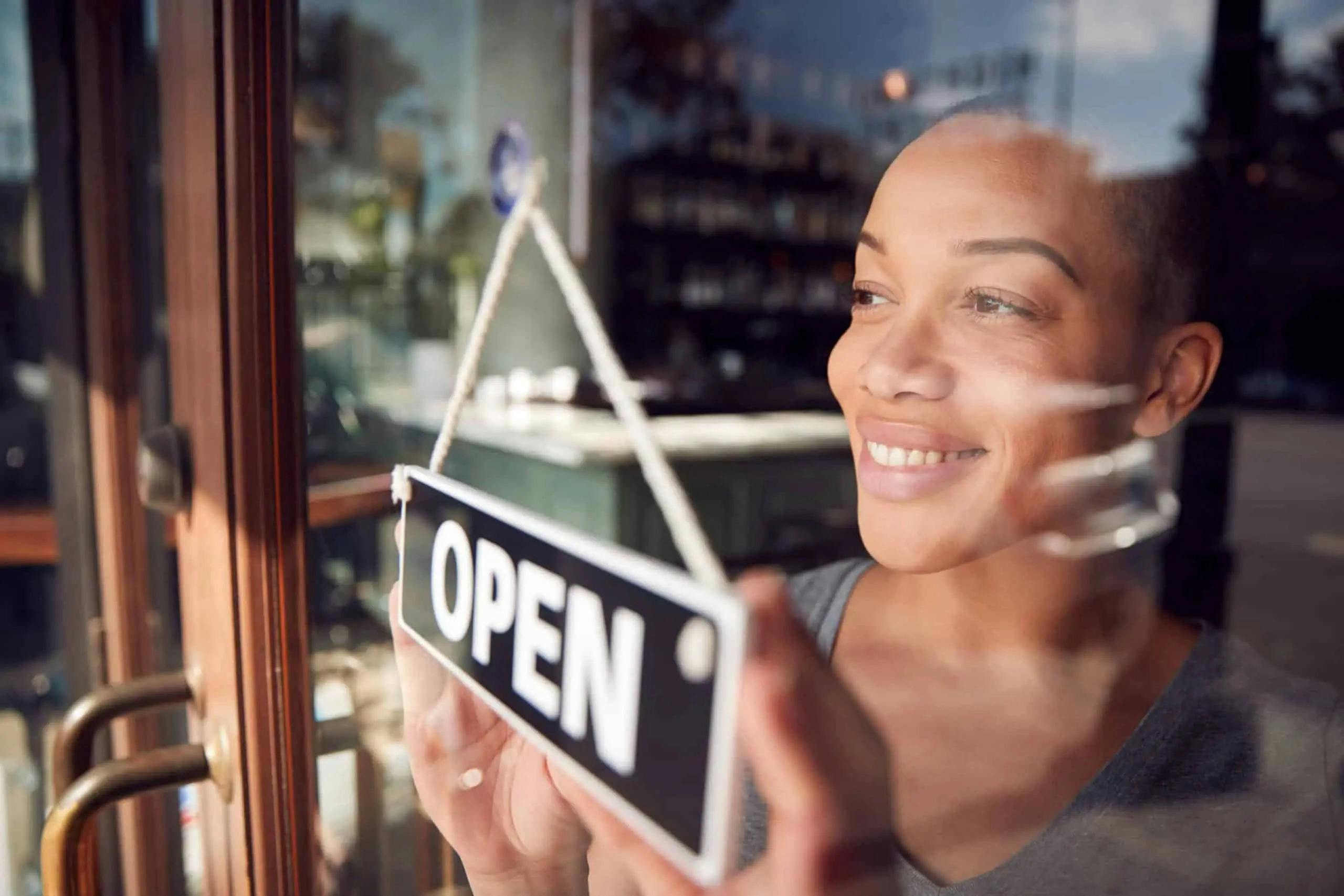 Black woman business owner switching open sign to open
