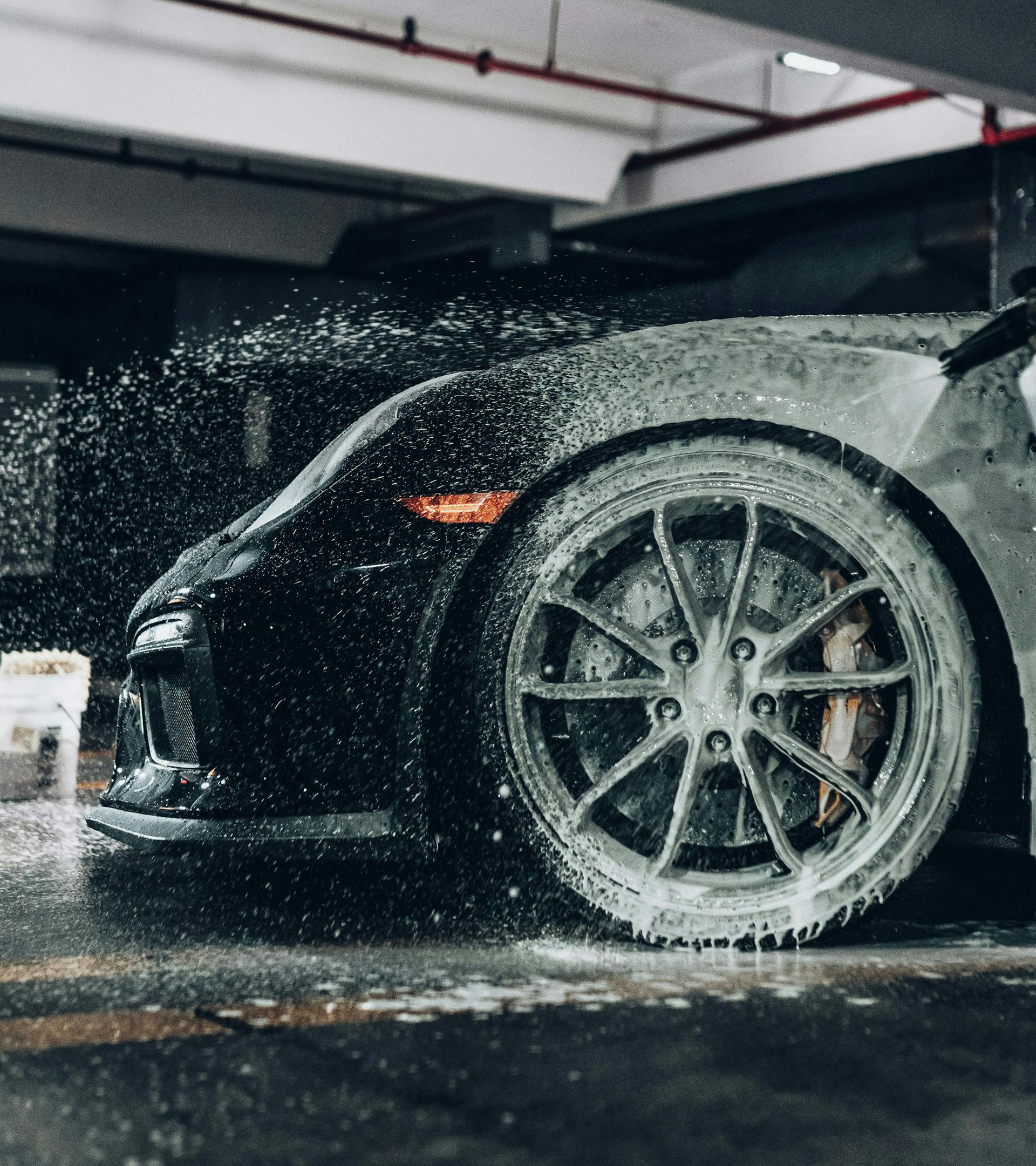Picture of a car's driver side wheel covered with suds in a garage of sometype