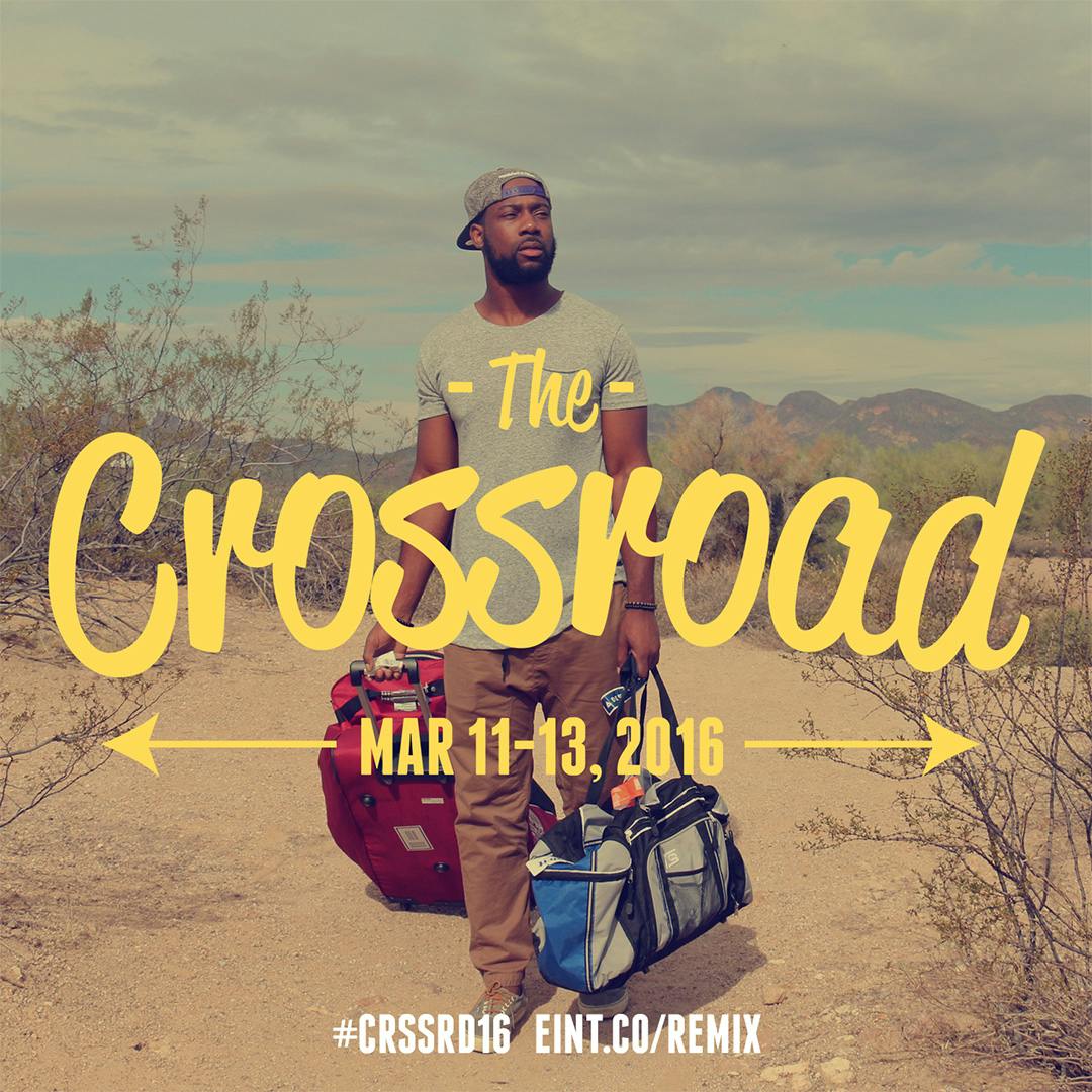 A man in the desert looking distraught carrying a rolling suitcase and duffle bag with the text "The Crossroad, Mar 11-13, 2016"