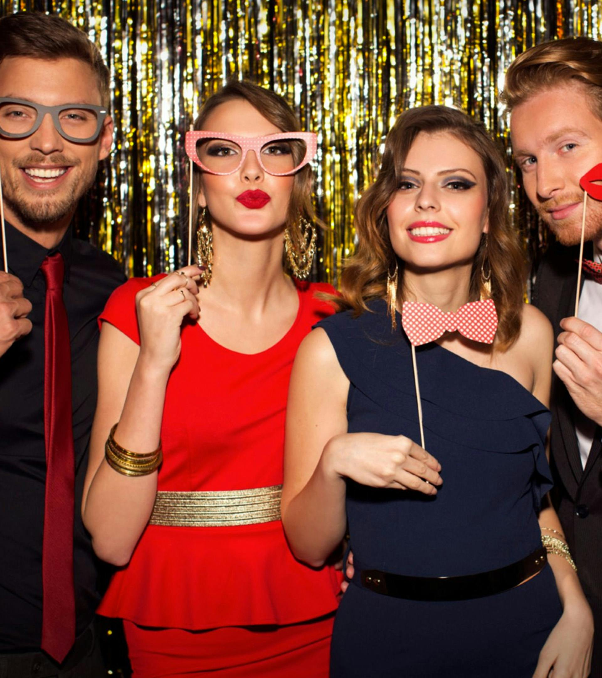Group of people with glasses, lips, and bow tie props taking a picture