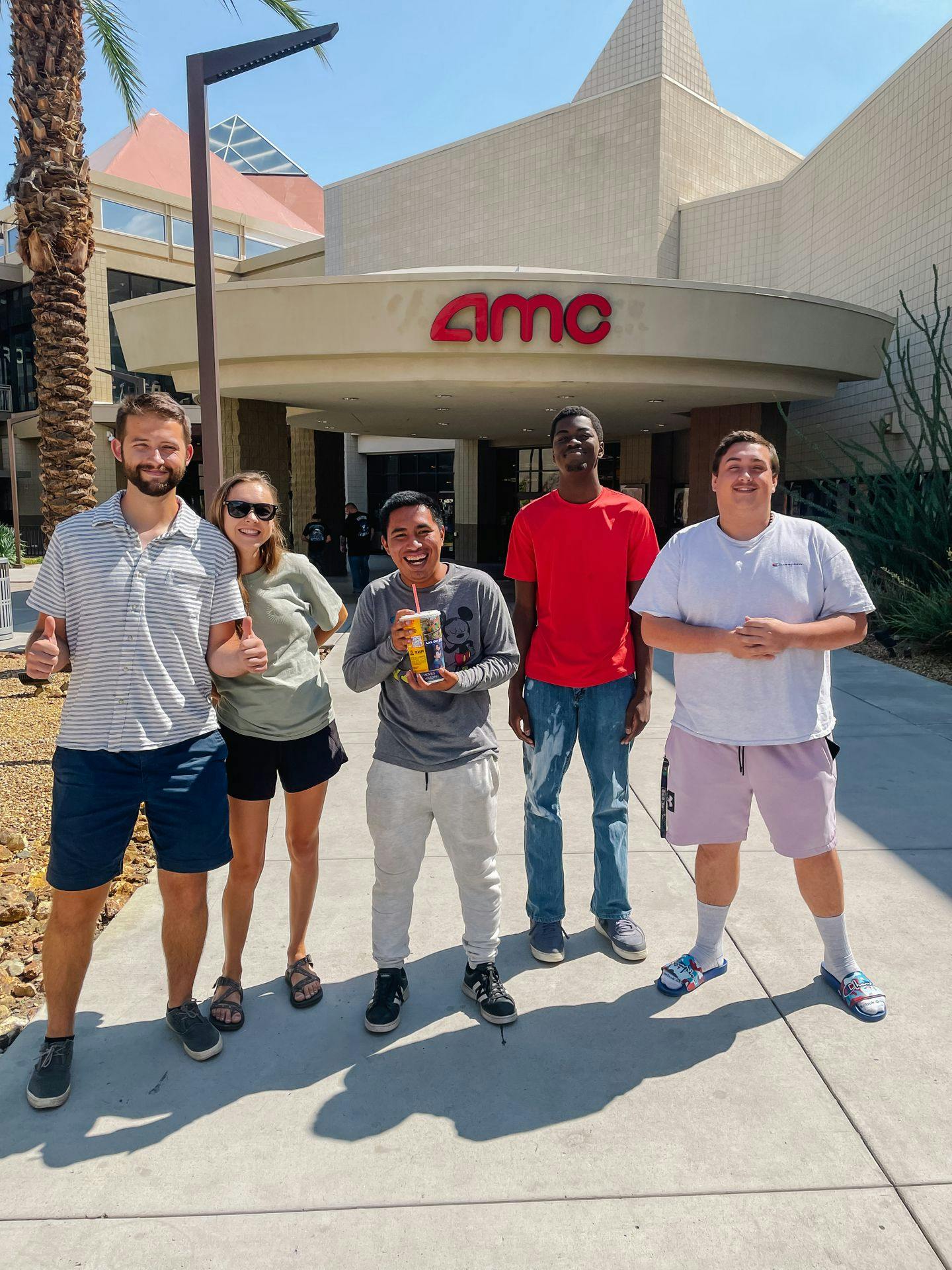 Group of 4 guys and 1 woman outside of a movie theater